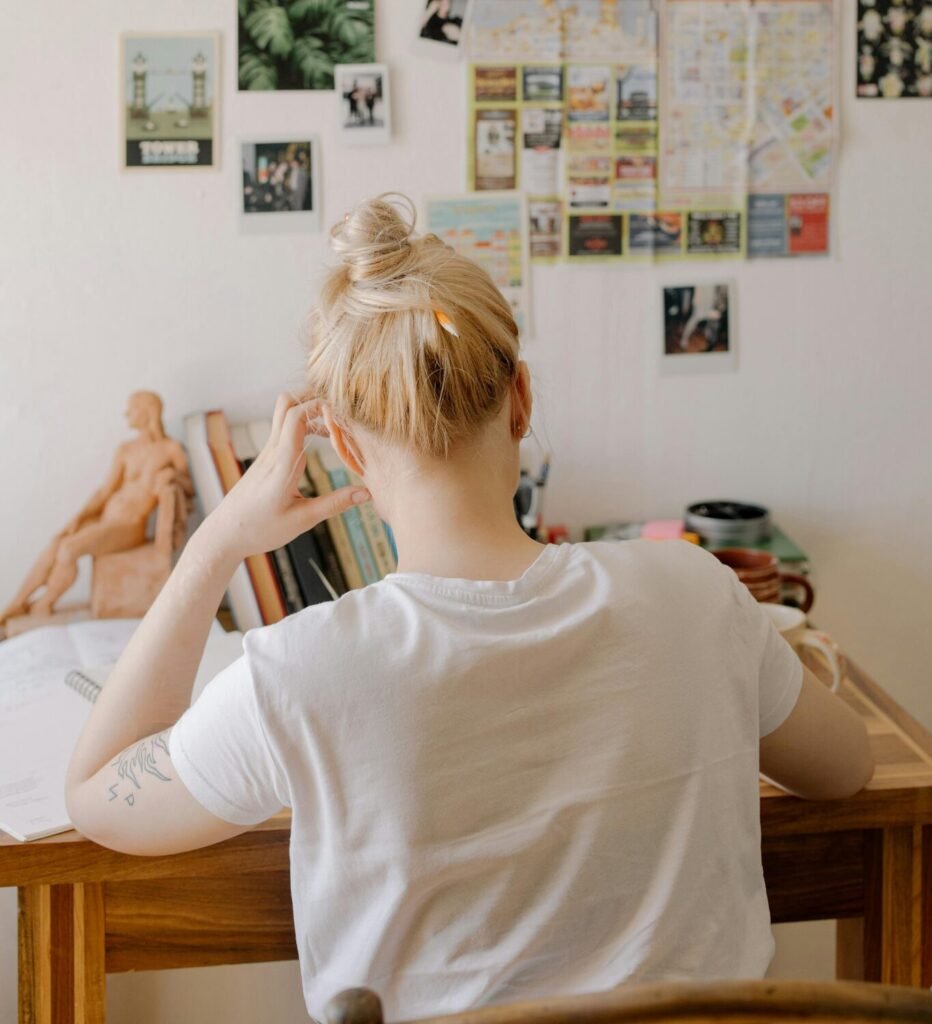 Artist sitting quietly at a desk, staring at a blank page — symbolizing self-blame, creative pressure, and being stuck in an art slump.